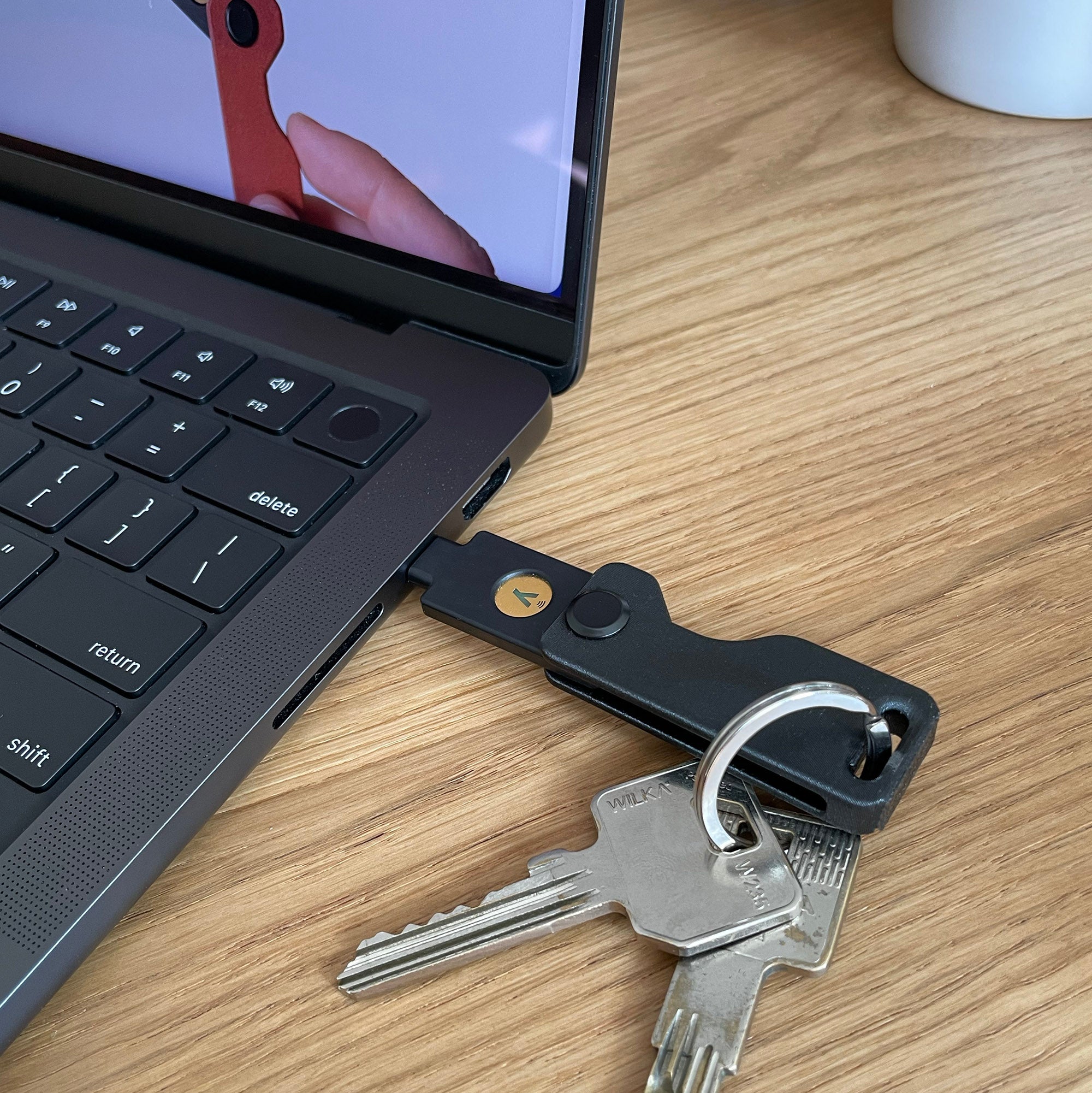Czarne etui Yubikey Lock Nest Orbit wpięte do macbooka pro air brelok klucze