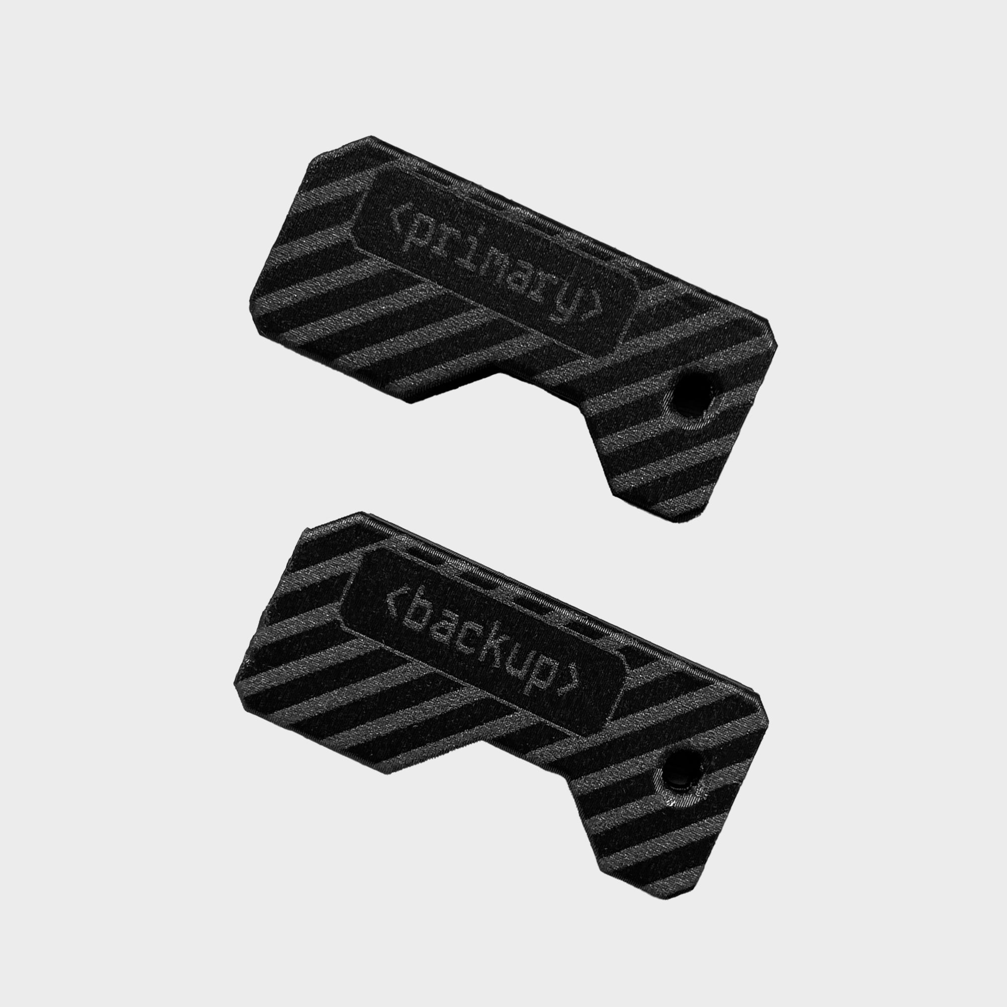 Lock Nest Czarny zestaw dwóch ochronnych etui na klucze YubiKey z grawerem „primary” oraz „backup”. Widoczny klucz YubiKey 5C NFC oraz YubiKey 5 NFC w wersji USB-A wysunięte z obudów. Idealne rozwiązanie do odróżnienia klucza głównego od zapasowego.