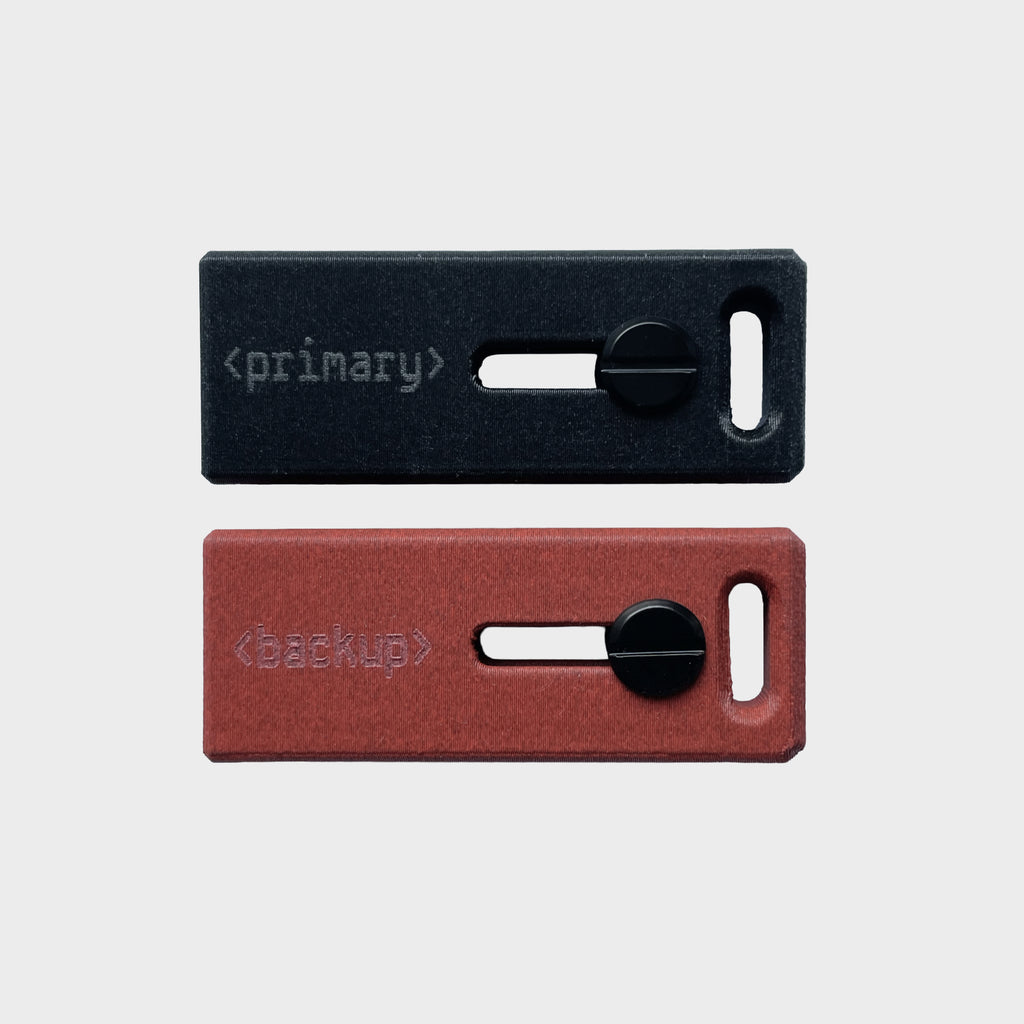 Lock Nest Slide Duo Primary Backup zestaw dwóch etui w kolorze czarnym primary i czerwonym backup. Pełna ochrona dla Twoich kluczy sprzętowych YubiKey